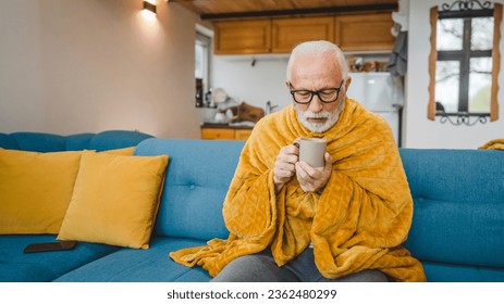 one caucasian male senior man sit on sofa bed at home hold cup of tea common cold sneezing sick caught cold - Powered by Shutterstock