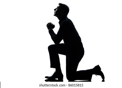 one caucasian man kneeling praying  full length silhouette in studio isolated white background