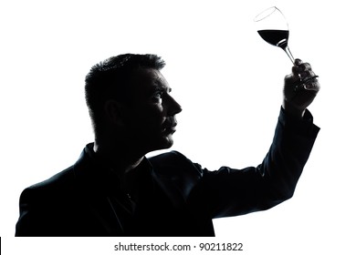 One Caucasian Man Portrait Silhouette Tasting  Looking At His Glass Of Red Wine In Studio Isolated White Background