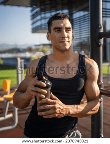 One caucasian man young male athlete take a brake during outdoor training in the park outdoor gym hold supplement shaker in hand happy confident strong copy space