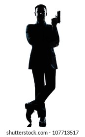 one caucasian secret agent in a james bond posture holding gun full length silhouette in studio isolated white background