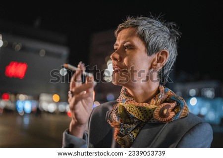 One caucasian senior woman modern female with gray hair stand in the city at night have a cigarette smoking tobacco nicotine addiction concept copy space
