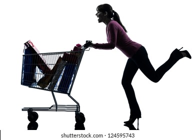 One Caucasian Woman With Full Shopping Cart In Silhouette Studio Isolated On White Background