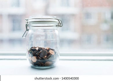 Lot Of One Cent Coins In A Glasses Jar By A Window