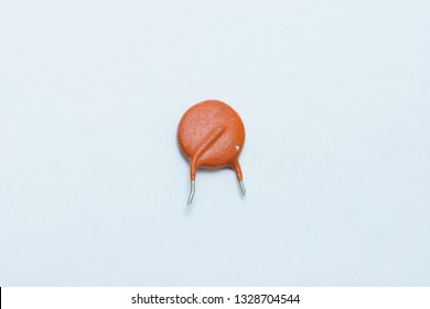 One ceramic capacitor. Orange color. On white background