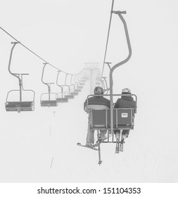 One of chair lifts in a ski resort of a valley of Zillertal in the fog - Mayrhofen region, Austria (black and white)
