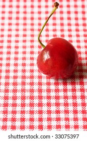One cherry on red gingham cloth