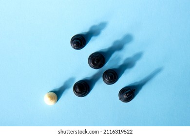 One Chess Piece Against Black Chess Pieces On A Blue Background With Contrasting Shadows. Abstract Background. Concept Of Leadership