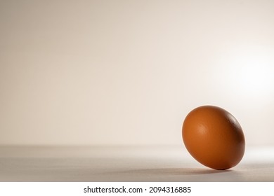 One Chicken, Brown Egg, On A Gray Background. A Brown, Chicken Egg Rolls On A Light Base.