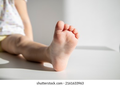 One child's foot on a white background. Child sitting on the floor