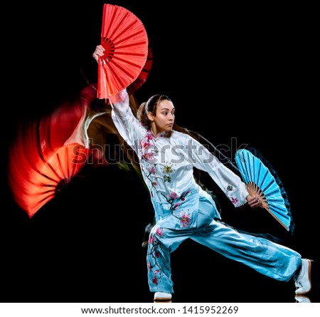 one chinese woman partacticing  Tai Chi Chuan Tadjiquan posture studio shot isolated on black background  with light painting effect