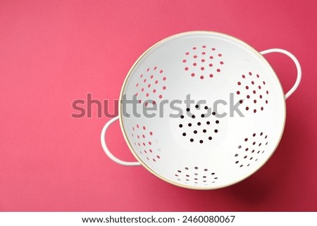 One clean empty colander on pink table, top view. Space for text
