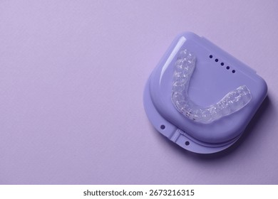One clear aligner and retainer case on violet background, top view. Space for text