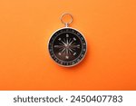 One compass on orange background, top view. Tourist equipment