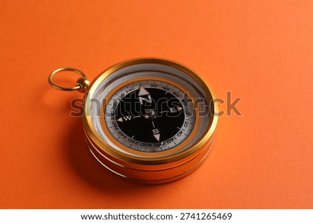 One compass on orange background, closeup view