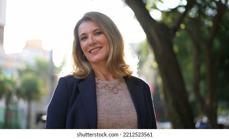 One Confident Mature Woman Standing Outdoors In Sunlight Portrait Face Closeup Looking At Camera. Senior Female Executive Entrepreneur