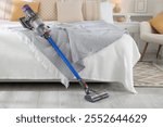 One cordless vacuum cleaner leaning on bed indoors