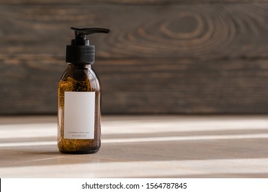 One cosmetic dark amber glass bottle on wooden background. Closeup, copyspace. Beauty blog, salon treatment concept, minimalism brand packaging mock up