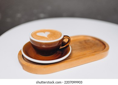 One Cup Of Cappuccino With Latte Art. Coffee In Ceramic Cup On Wooden Tray In Cafe. Concept Of Easy Breakfast In City Or At Home