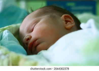One day old newborn boy infant is sleeping with anti grasping gloves