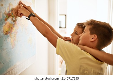 One Day We Can Travel The World Together. Shot Of Two Little Boys Looking At A Map On The Wall At Home.