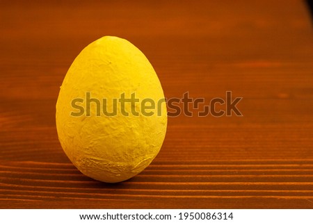 One decorative yellow egg on a wooden background.