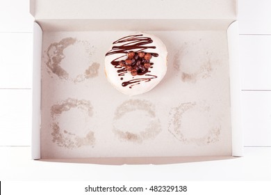 One Delicious Donut With Sprinkles In A Empty Box On A White Wooden Background. Top View With Copyspace