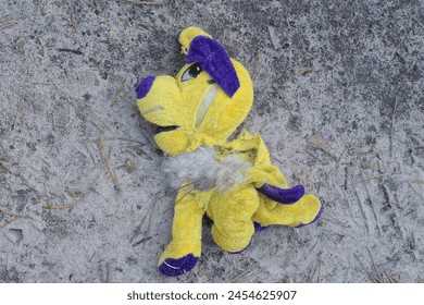 one dirty old torn yellow plush toy dog lies on the ground  - Powered by Shutterstock