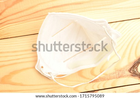 One disposable medical respirator of white color, close-up, on a wooden table.