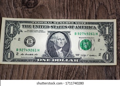 one dollar bill with a lit face on a wooden background