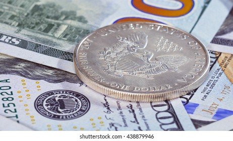 One dollar silver American eagle coin over bank notes background