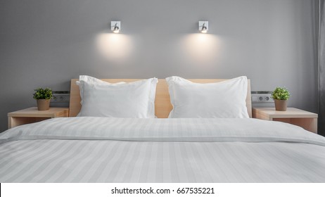 One Double Bed In A Hotel Near Flowers On The Nightstand