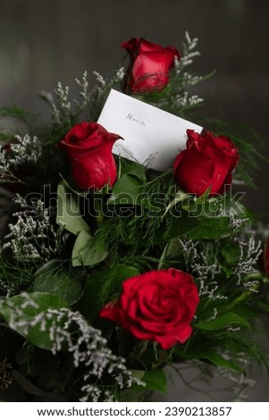 One dozen deep red roses in a pale blue vase on a table