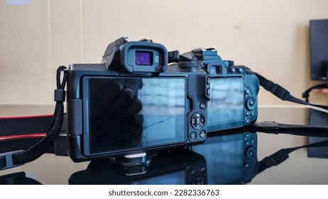 One DSLR and one Mirrorless camera in a table. the reflection can be seen in the glass