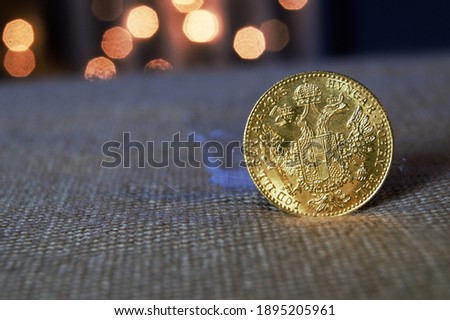 One ducat gold coin. 
a small, gold coin as a way of investing capital. 
ducat on a background of blurred lights. Bokeh in the background. Investing background [[stock_photo]] © 