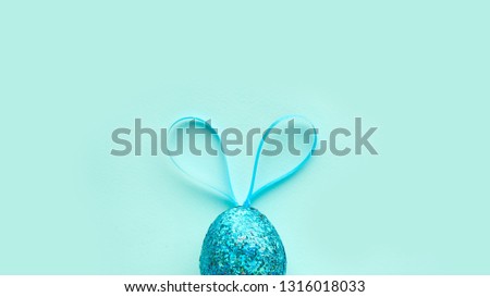 one easter egg on a turquoise background, with bunny ears. minimalism concept