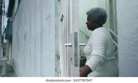 One elderly black lady opening residence front door, arriving home from urban sidewalk street. 80s African American woman returns to South American house after daily routine activity - Powered by Shutterstock