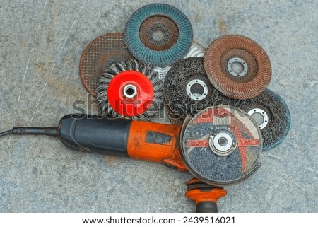 one electric orange dangerous grinding machine with sharp different cutting discs lie on a gray iron table on the street during the day