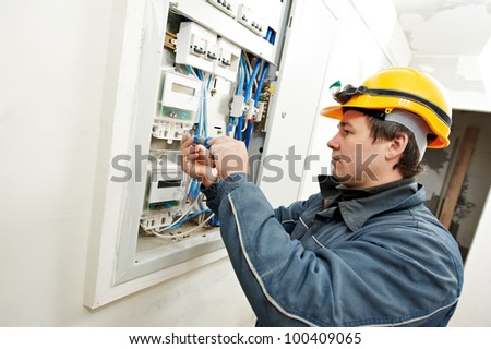 One electrician builder at work installing energy saving meter into electric line distribution fuseboard