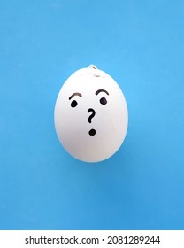 
 One emotion-drawn egg with a surprised expression featuring a question mark is set against a light blue paper background. Something went wrong, it cracked. Copy space.