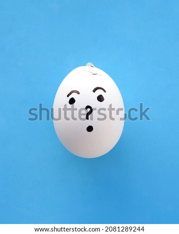 
 One emotion-drawn egg with a surprised expression featuring a question mark is set against a light blue paper background. Something went wrong, it cracked. Copy space.