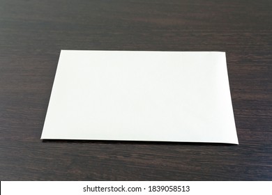 One Empty Blank Sheet Of Paper Placed On The Dark Wooden Surface Of The Office Desk. Empty Layout Mockup On Textured Vintage Paper Surface. Watercolor Paper Template Top View With Copy Space