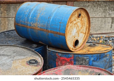 one empty rusty open  blue discarded round industrial painted iron old oil hazardous barrel lies on other barrels in a dump during the day on the street