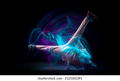 One energy young flexible sportive man dancing hip-hop or breakdance in white outfit on dark background in mixed blue neon light. Concept of sport, art, action, moves, youth culture. Banner for ad - Powered by Shutterstock