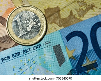 One eu coin lies on twenty euro bill banknote