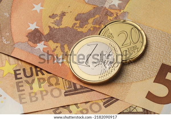 One euro and twenty cents coins on the red fifty\
paper bills.