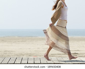 One Female Walking At The Beach Barefoot With Dress