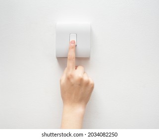 One finger switching one off wall-mounted light switch in a close up conceptual view of power, energy and electricity consumption - Shutterstock ID 2034082250