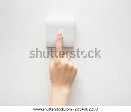 One finger switching one off wall-mounted light switch in a close up conceptual view of power, energy and electricity consumption