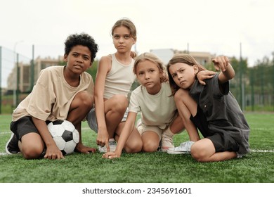 One of four active schoolkids pointing forwards while explaining something to intercultural friends during break between trainings - Powered by Shutterstock